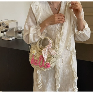 Detail of straw handbag featuring pink hello embroidery, floral scarf and drawstring lining