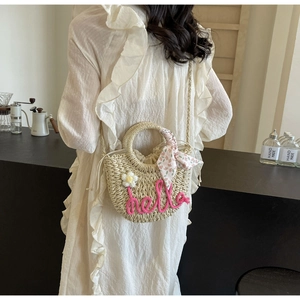 Detail of straw half-moon bag with pink hello embroidery and floral silk scarf accessory