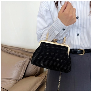Close-up of elegant black rhinestone evening bag with gold chain and metal clasp
