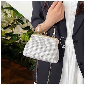 Close-up of sparkling silver crystal evening bag with golden handle and fine chain strap