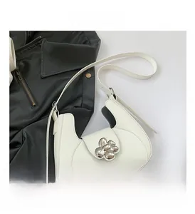 Détail du sac demi-lune blanc avec une grande boucle métallique argentée en forme de fleur