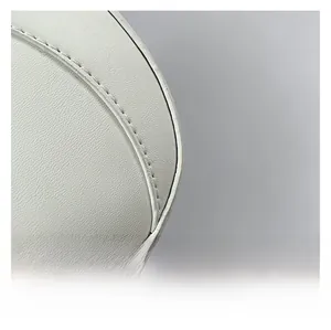 Détail macro du cuir synthétique blanc grainé avec des coutures soignées sur le sac selle