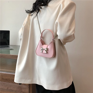 Mini sac bandoulière rose avec boucle nœud argenté et chaîne sur mannequin femme