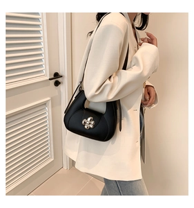 Gros plan sur un sac sous le bras en cuir noir avec boucle fleur argentée brillante