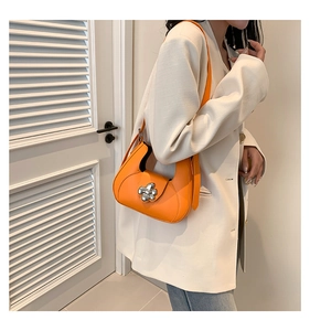 Gros plan d'un sac demi-lune orange avec une boucle florale argentée élégante