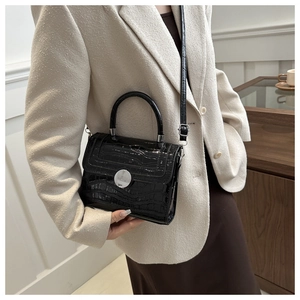 Sac à main classique noir à texture crocodile assorti à un élégant tailleur beige