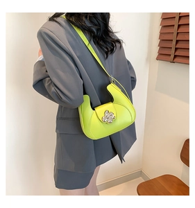 Détail du sac hobo vert fluo avec boucle florale argentée sur texture de cuir lisse