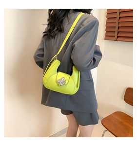 Détail du sac demi-lune vert néon avec boucle fleur argentée et bandoulière fine