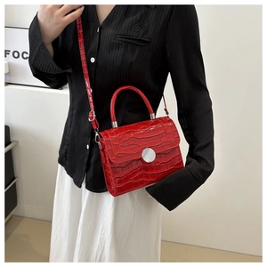 Detail of red crocodile texture handbag with glossy finish and silver circular metal lock