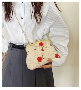 Sac bandoulière tressé beige avec broderie florale et chaîne dorée porté par un mannequin