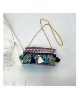 Close-up of ethnic woven crossbody bag with colorful fringe tassels and gold chain strap