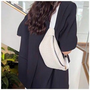 Détail de la texture tressée du sac blanc avec fermeture dorée et bandoulière large