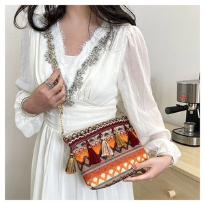 Close-up of ethnic bohemian knit crossbody bag with colorful tassels and golden chain strap