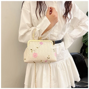 Détail du sac en paille avec broderie florale, poignée en métal et chaîne dorée