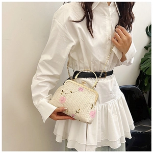 Détail du sac en paille tressée avec broderie florale rose et fermoir en métal vintage