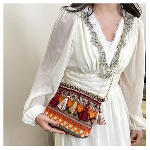 Detail of ethnic woven shoulder bag with colorful tassels and golden metal chain strap