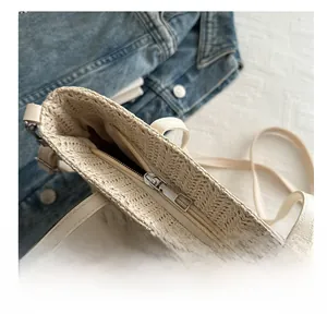 Close-up of smooth silver zipper closure on a beige straw tote bag with inner lining