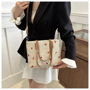 Detailed view of handmade straw tote bag with cherry embroidery and brown leather straps