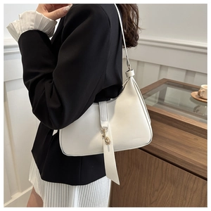 Detail of white leather underarm bag featuring golden metal hook and zip closure