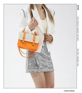Elegante borsa a tracolla arancione in paglia e ecopelle con un abito metallizzato