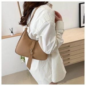 Side view of a khaki moon-shaped underarm bag with decorative metal buckle and strap