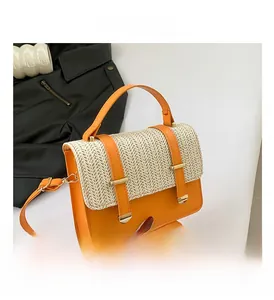 Dettaglio della patta in paglia intrecciata e borsa in pelle arancione con fibbie d'oro