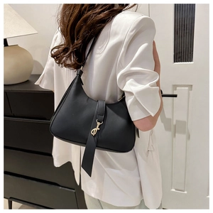 Detail of black leather underarm bag featuring a gold lobster clasp buckle and modern strap