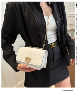 Close-up of white quilted leather crossbody bag with golden chain strap and twist lock