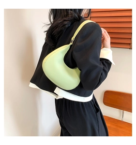 Close-up of pistachio green crescent shoulder bag styled on a model's shoulder