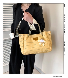 Detail of yellow checkered canvas tote with rope handles and cute doll charm