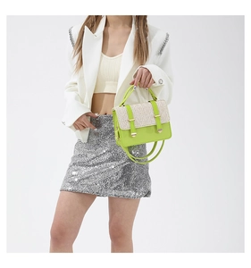 Dettaglio borsa in paglia a contrasto verde neon con fibbie dorate e abito bianco