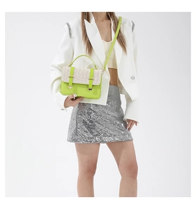 Borsa a tracolla intrecciata verde neon e beige indossata con blazer bianco