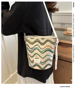 Detail of multi-color wavy knit bucket bag with white leather trim and slim strap