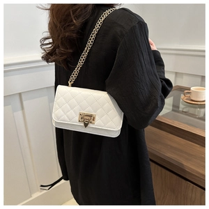 Detail of white quilted chain bag showing the golden twist lock and textured PU leather