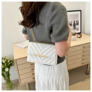 Rear view of a white quilted crossbody bag with gold chain and chevron leather pattern