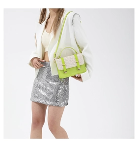 Modella con borsa a tracolla verde neon e patta in paglia beige intrecciata e manico