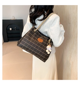 Detail of dark brown checkered tote bag with hemp rope strap and white pompom on a model