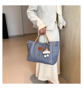 Detail of grey-blue checkered tote bag featuring rope handles and a cute plush charm