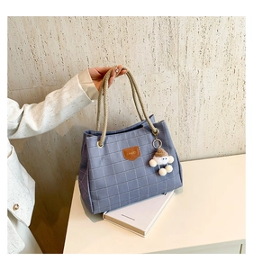 Detail of blue plaid tote bag with rope handles and cute plush doll charm