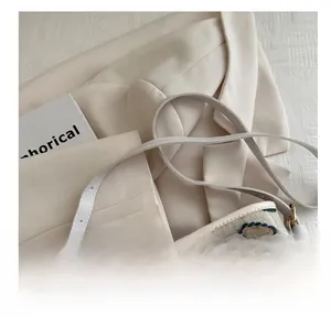Detailed view of the wavy embroidery and leather strap with gold hardware on the bag