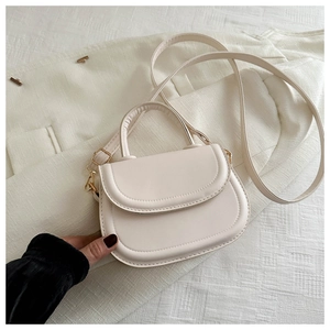 Detail of beige leather saddle bag showing matte texture and golden hardware accents