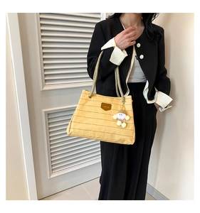 Close-up of yellow plaid canvas tote bag with thick rope handles and plush pendant
