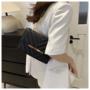 Detail view of black V-quilted shoulder bag with gold hardware and chain strap