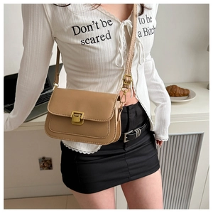 Detail of khaki flap crossbody bag with gold buckle and adjustable strap on a model