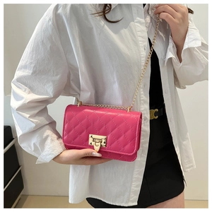 Detail of fuchsia quilted crossbody bag with gold chain strap and metal twist lock