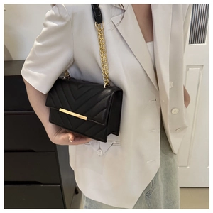 Detail of black V-quilted leather flap bag with gold metal bar and chain strap for women