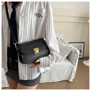 Detail view of the black leather crossbody bag with a refined golden metal push-lock closure
