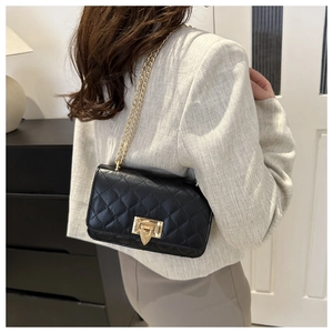 Detail of classic black quilted shoulder bag with gold chain strap and metal lock