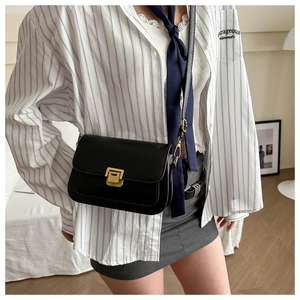 Close-up of black crossbody flap bag featuring a square gold metal clasp on model