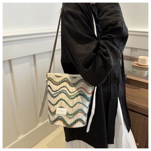 Detail shot of bohemian knit bucket bag with wave patterns and white leather strap